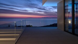 A modern building with a glass balcony overlooking a body of water at dusk. - The Sall Villa - 2 Bedrooms with Private Pool & Sea View (Volimes)