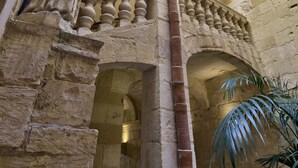 A stone building with a central column, arches, and a balcony with balustrades. - Rose Of Rhodes Palazzo  (Valletta)