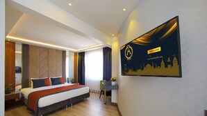 A modern hotel room with a large bed, a desk, and a wall-mounted TV displaying the hotel's logo and website. - Eyfel Hotel (Istanbul)