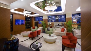 A modern hotel lobby with a variety of seating options, a large TV screen, and a ceiling with unique lighting fixtures. - Eyfel Hotel (Istanbul)