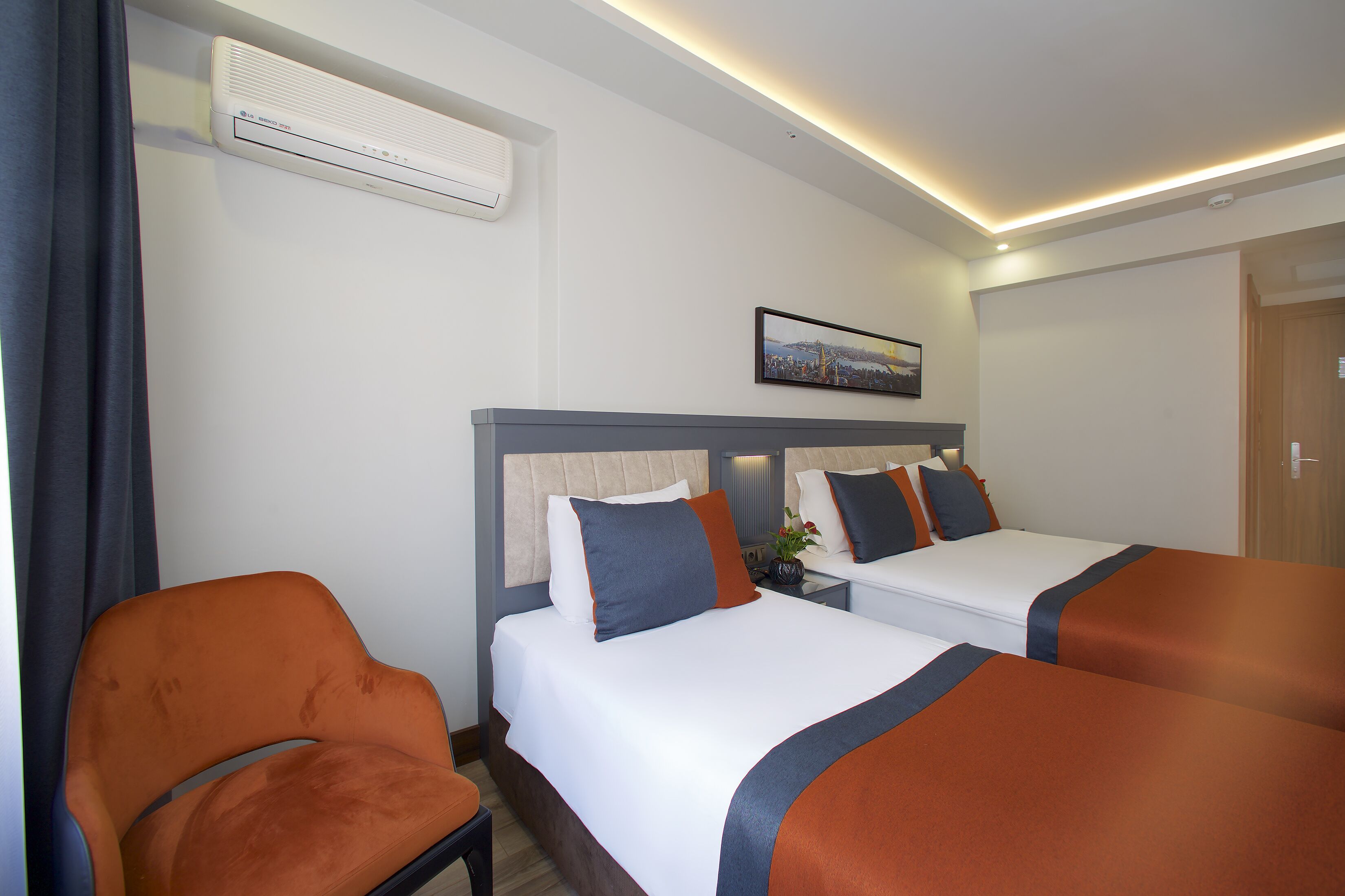 Una habitación de hotel con dos camas, una silla, aire acondicionado y un cuadro en la pared.