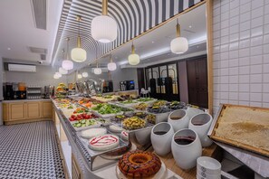 Ein reichhaltiges Buffet mit Speisen und Getränken, eine Kaffeemaschine und ein Kuchen auf der Anrichte.
