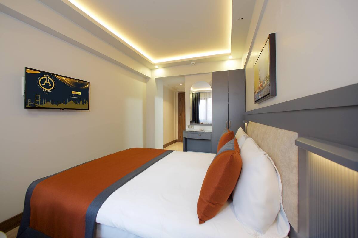 A hotel room with a bed, a nightstand, a mirror, and a framed picture on the wall.