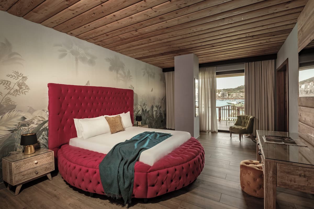 Quarto com cama redonda, teto de madeira e varanda com vista.