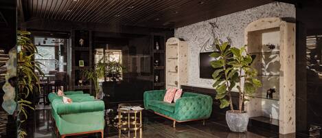 A modern living room with green sofas, a coffee table, and potted plants.
