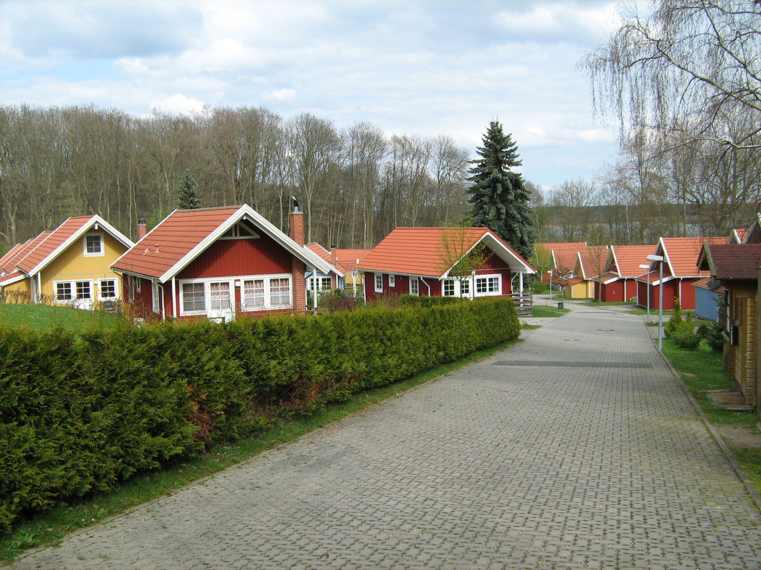 Uma fileira de casas de campo com telhados vermelhos e um caminho de paralelepípedos que leva a um gramado.