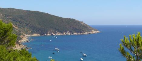 Un paisaje costero con vista despejada al mar, barcos y un terreno montañoso.