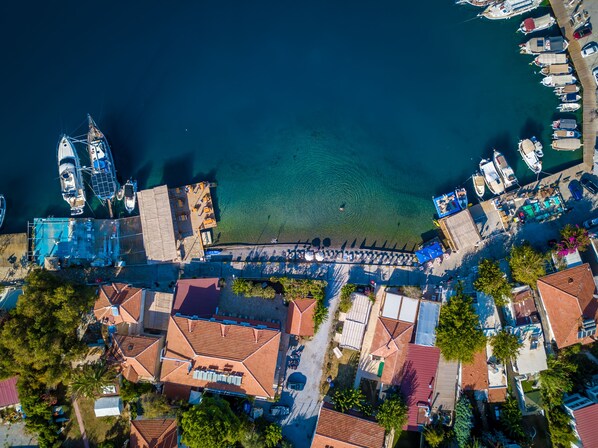Vista aérea de un pueblo costero con un puerto deportivo, edificios residenciales y un muelle.