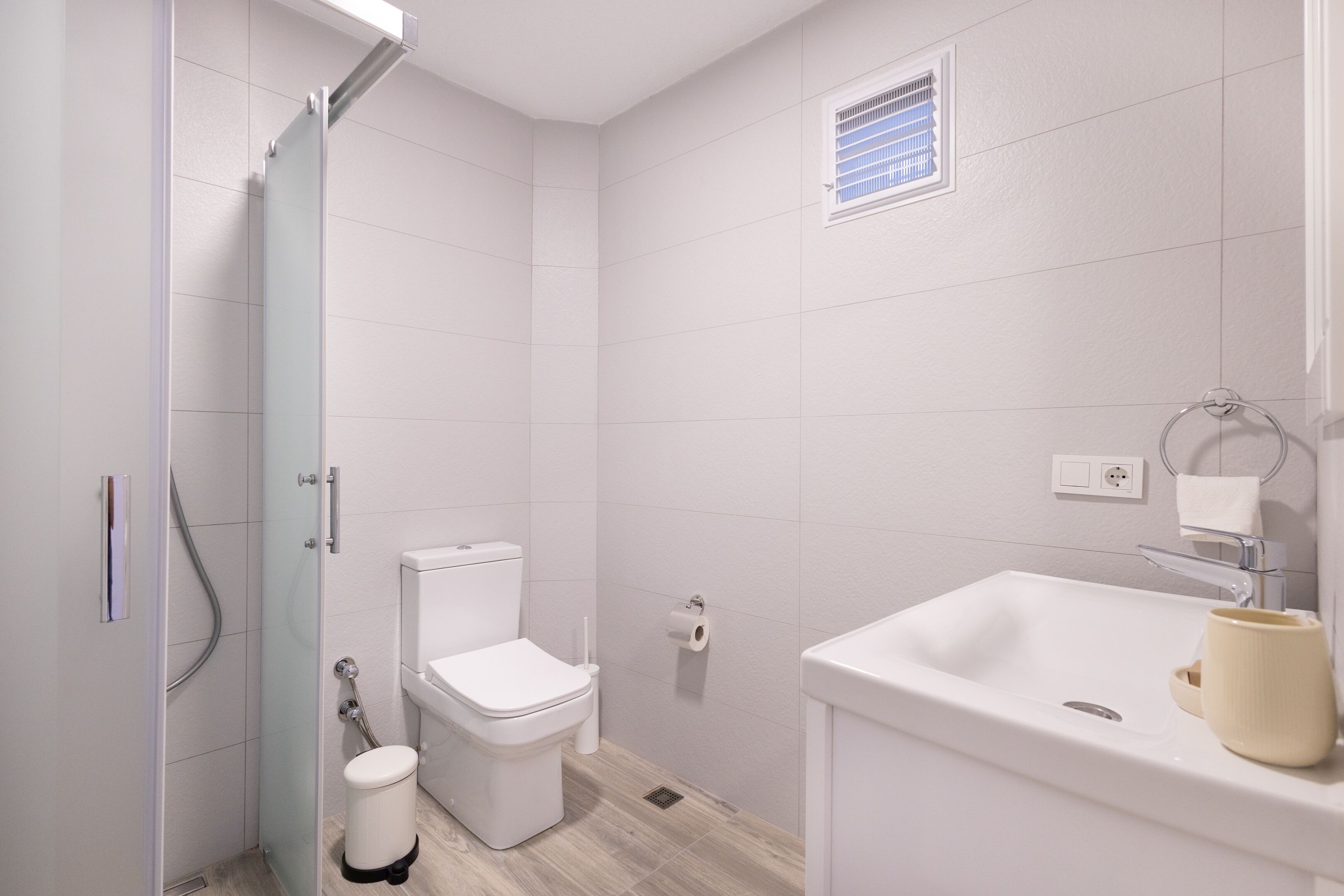 A modern bathroom with a toilet, shower, and sink.
