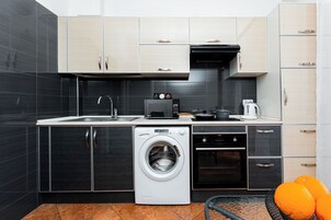 Een moderne keuken met een wasmachine, oven en koffiezetapparaat.