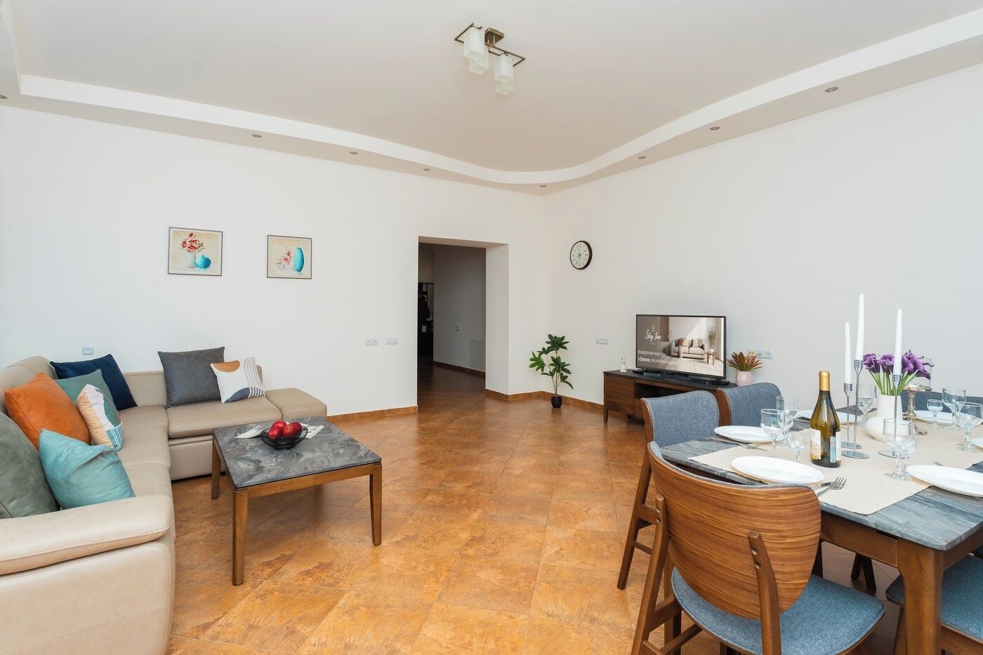 Een moderne woonkamer met een bank, salontafel en een eethoek gedekt voor een maaltijd.