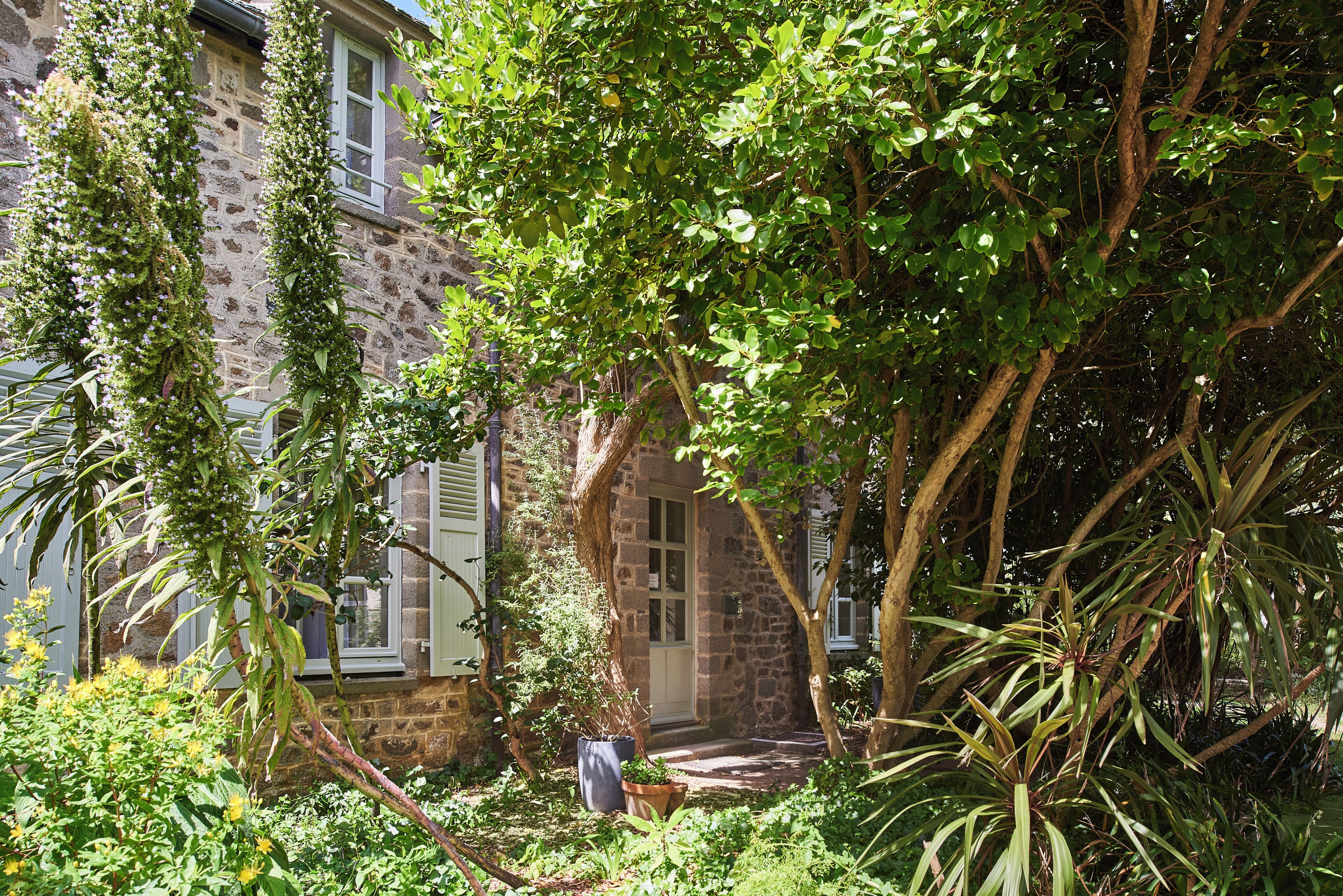 A stone building with a garden, a door, and a window.