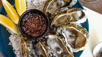 Lautasella on osteri, sitruunaviipaleita ja pieni kulho cocktailkastiketta.