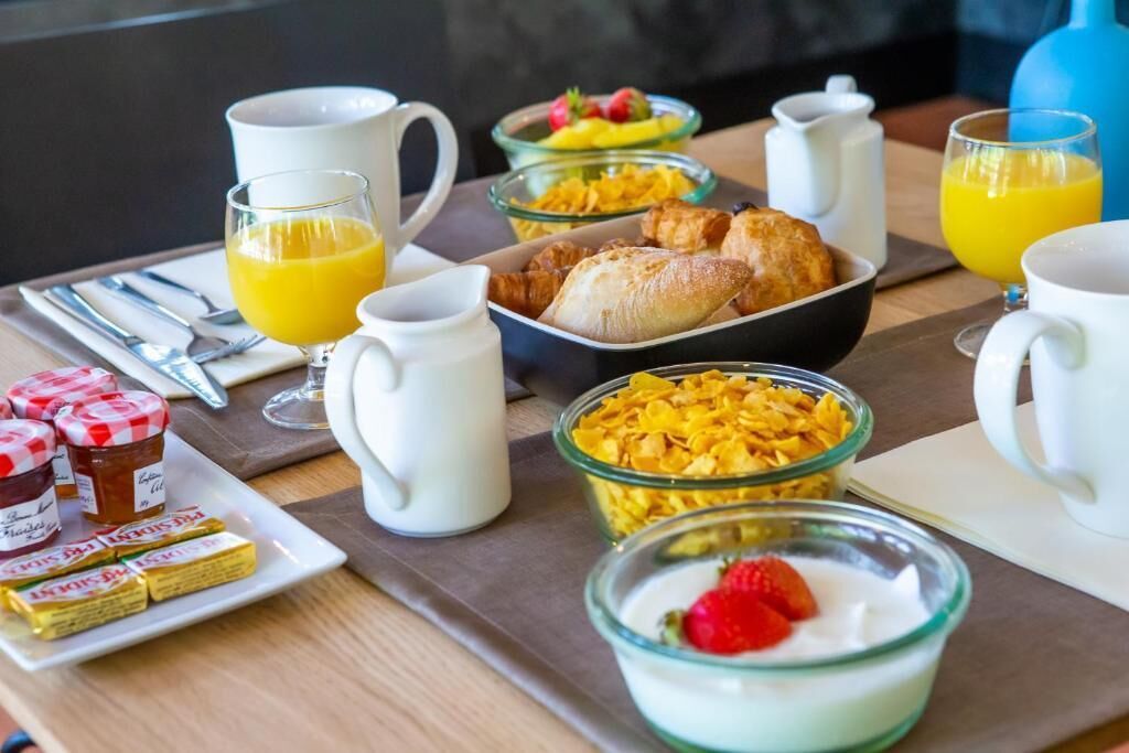 Ein Frühstücksbrett mit Müsli, Joghurt, Obst und Gebäck.