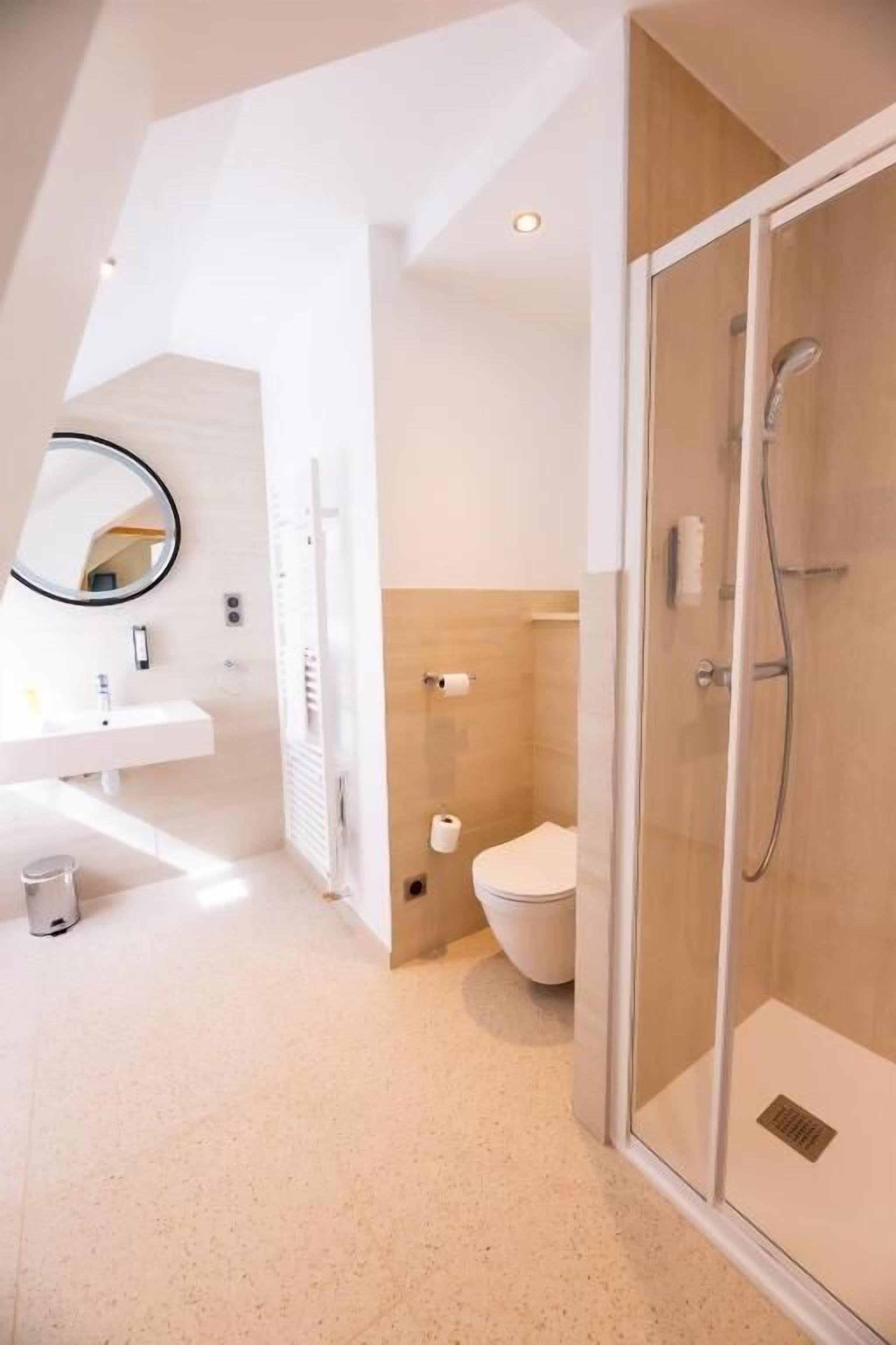 A modern bathroom with a glass shower enclosure, a white sink, and a toilet.