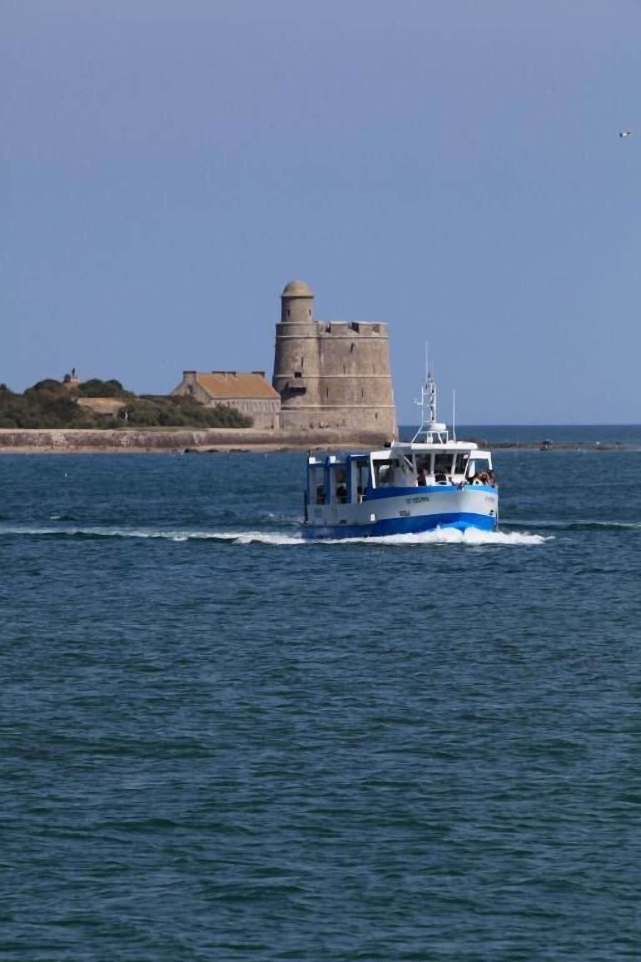 A boat with a blue and white color scheme, a lighthouse in the background, and calm water.