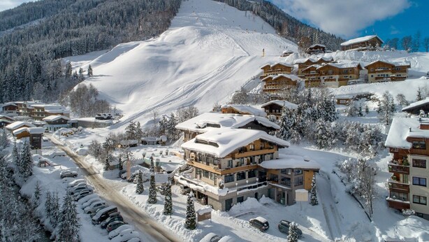 A snow-covered ski resort with multiple chalet-style buildings, a ski slope, and a clear sky. - Nice suite in Saalbach (Saalbach)