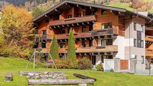 A multi-story hotel with wooden balconies, a stone facade, and a mountainous backdrop. - Nice suite in Saalbach (Saalbach)