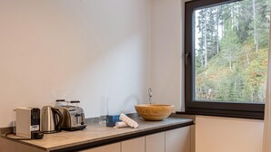A modern kitchen with a wooden bowl sink, a kettle, a toaster, and a coffee maker on the countertop. - Nice suite in Saalbach (Saalbach)