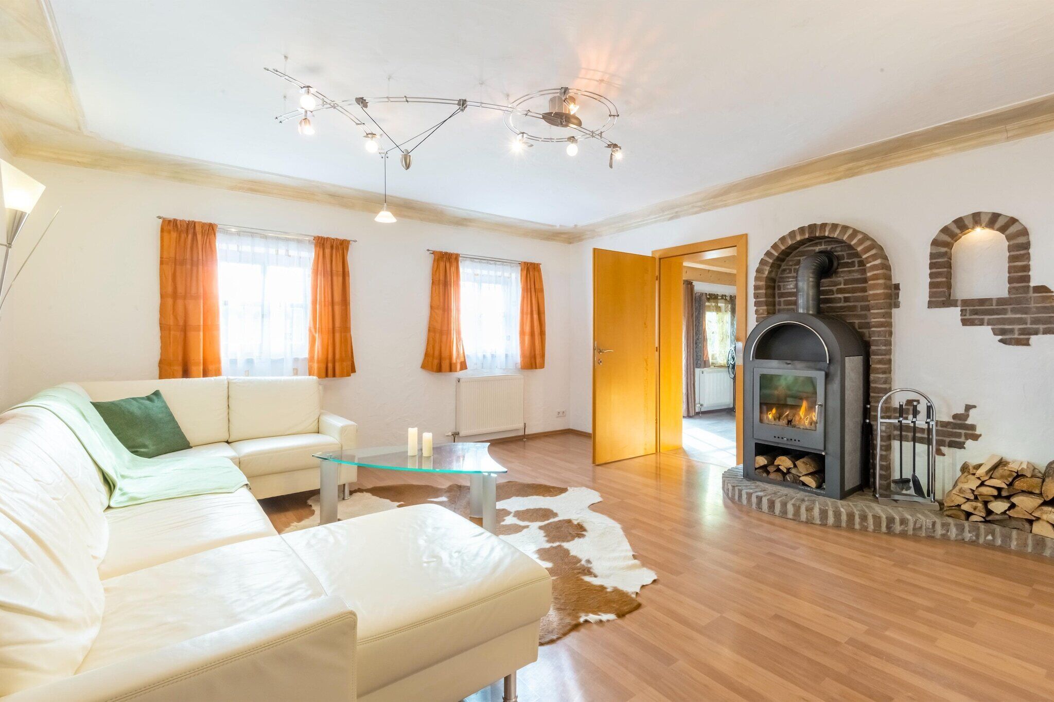 Ein modernes Wohnzimmer mit einem weißen Ledersofa, einem Glastisch und einem Kamin mit Ziegelverkleidung.