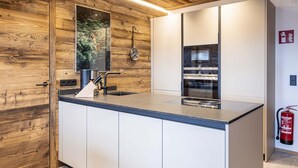 A modern kitchen with wooden accents, a built-in stove, and a stainless steel sink.