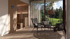 A modern living room with a large sliding glass door leading to a garden. There are two black chairs with cushions, a round woven rug, and a tall floor lamp.