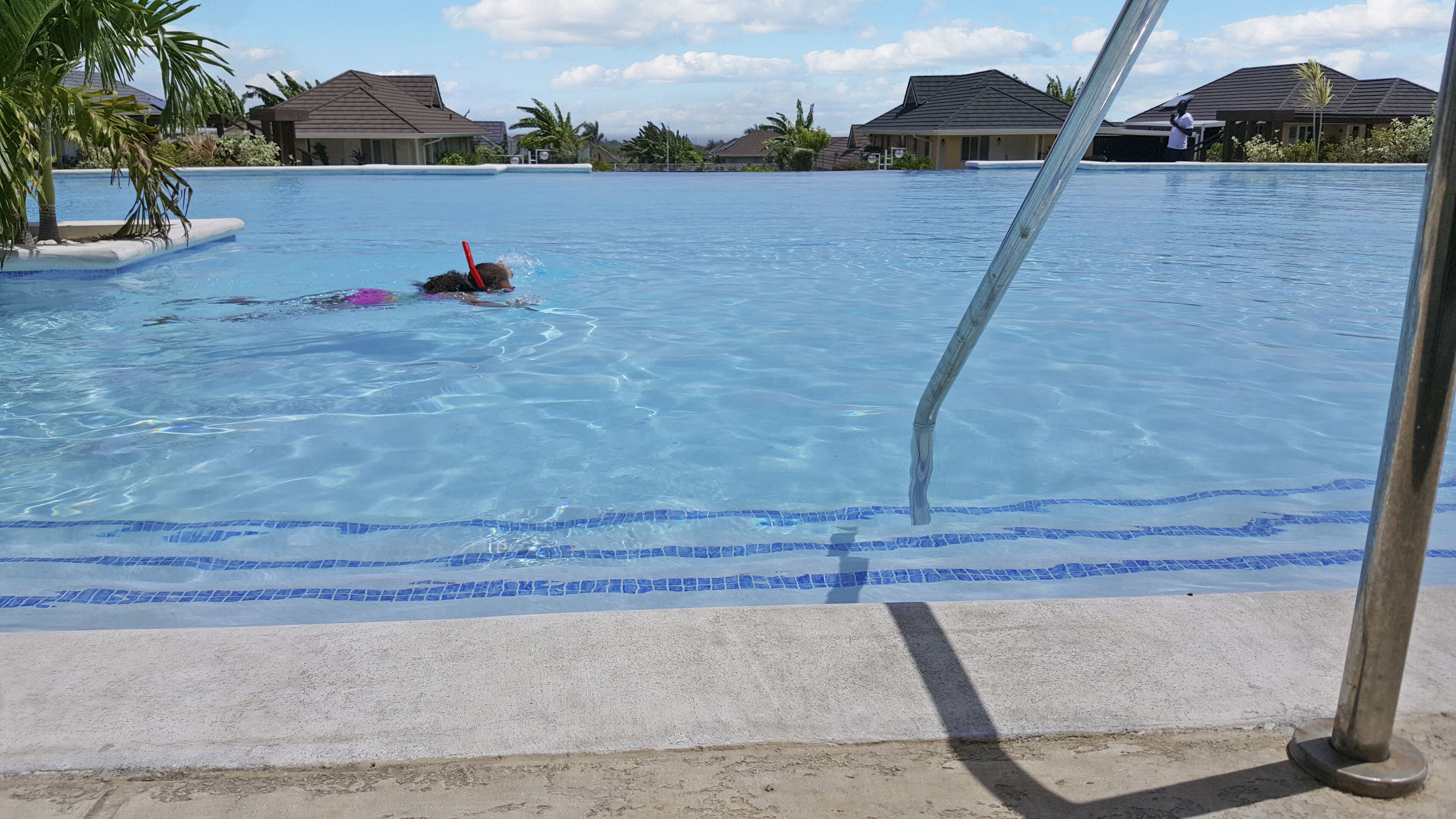 Una piscina con agua azul cristalina, rodeada de casas con tejados inclinados.