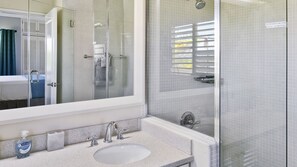 A modern bathroom with a large mirror, a sink, and a shower area.