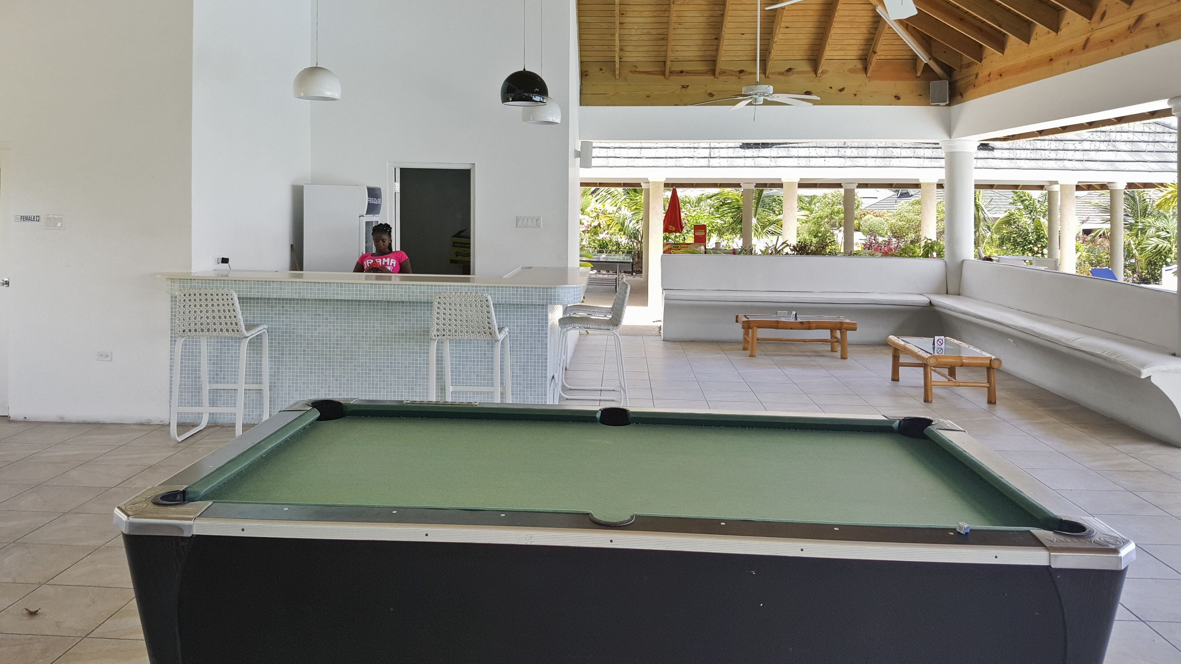 Une table de billard dans un espace extérieur abrité, avec un bar et des sièges.