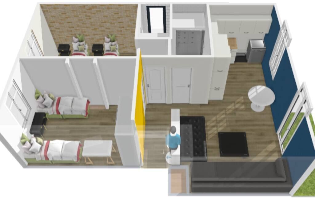 A modern hotel room with a kitchenette, a sitting area with a sofa and armchairs, a small dining table, and a view of the cityscape.