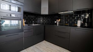 A modern kitchen with black cabinetry, a built-in oven, and a tiled backsplash. - Le Loft de St Jean - 2 bed and 2 bath (Cannes)