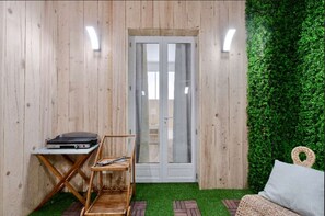 A room with wooden walls, a sliding glass door, a small table with a laptop, a chair, and a green wall. - St Nicolas - Cosy "Cabane de plage" avec A/C & Patio à 10 min to Palais  (Cannes)