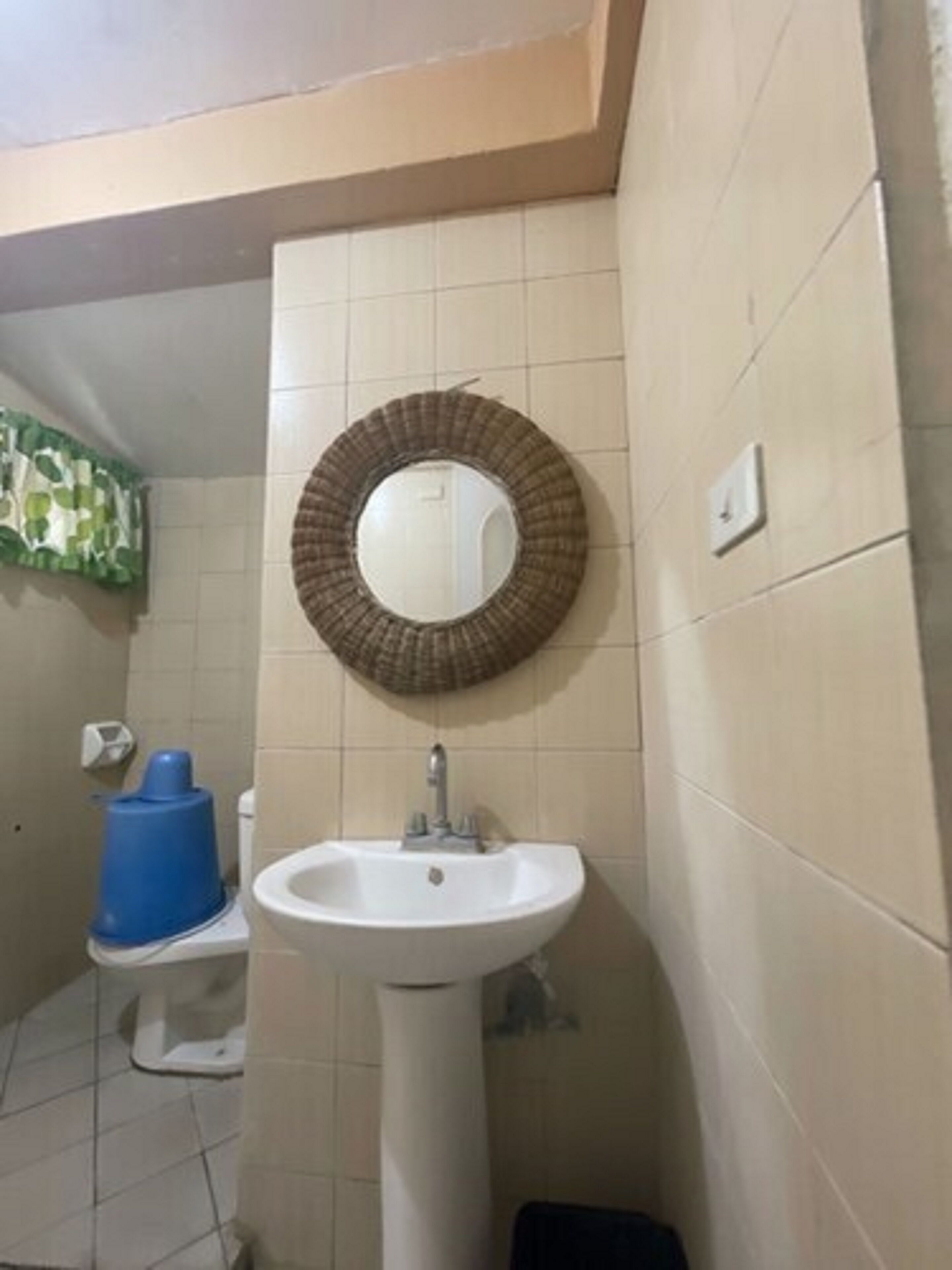 Un baño con un lavabo blanco, un espejo redondo y un inodoro.