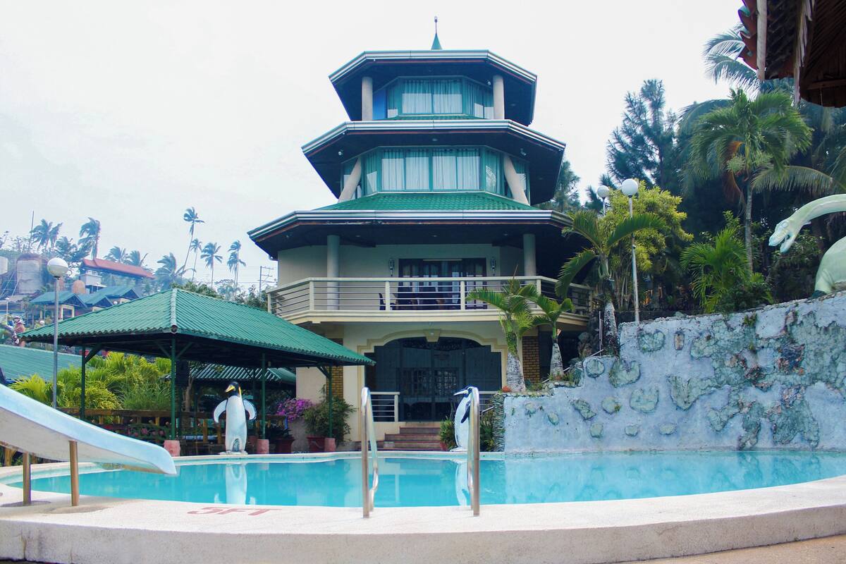 A multi-story building with a green roof, a swimming pool, and a slide.