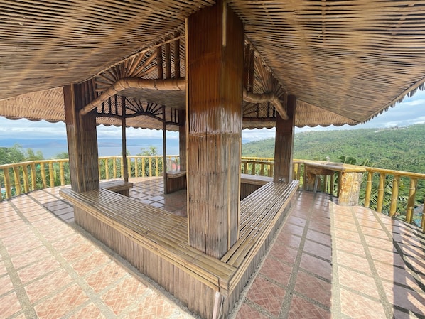 Un pabellón de madera con suelo de baldosas y vistas a un paisaje exuberante.
