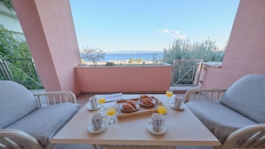 A breakfast table with croissants, orange juice, and coffee cups on a balcony overlooking the sea. - Holiday Seaview Apartment by Litto (Split)