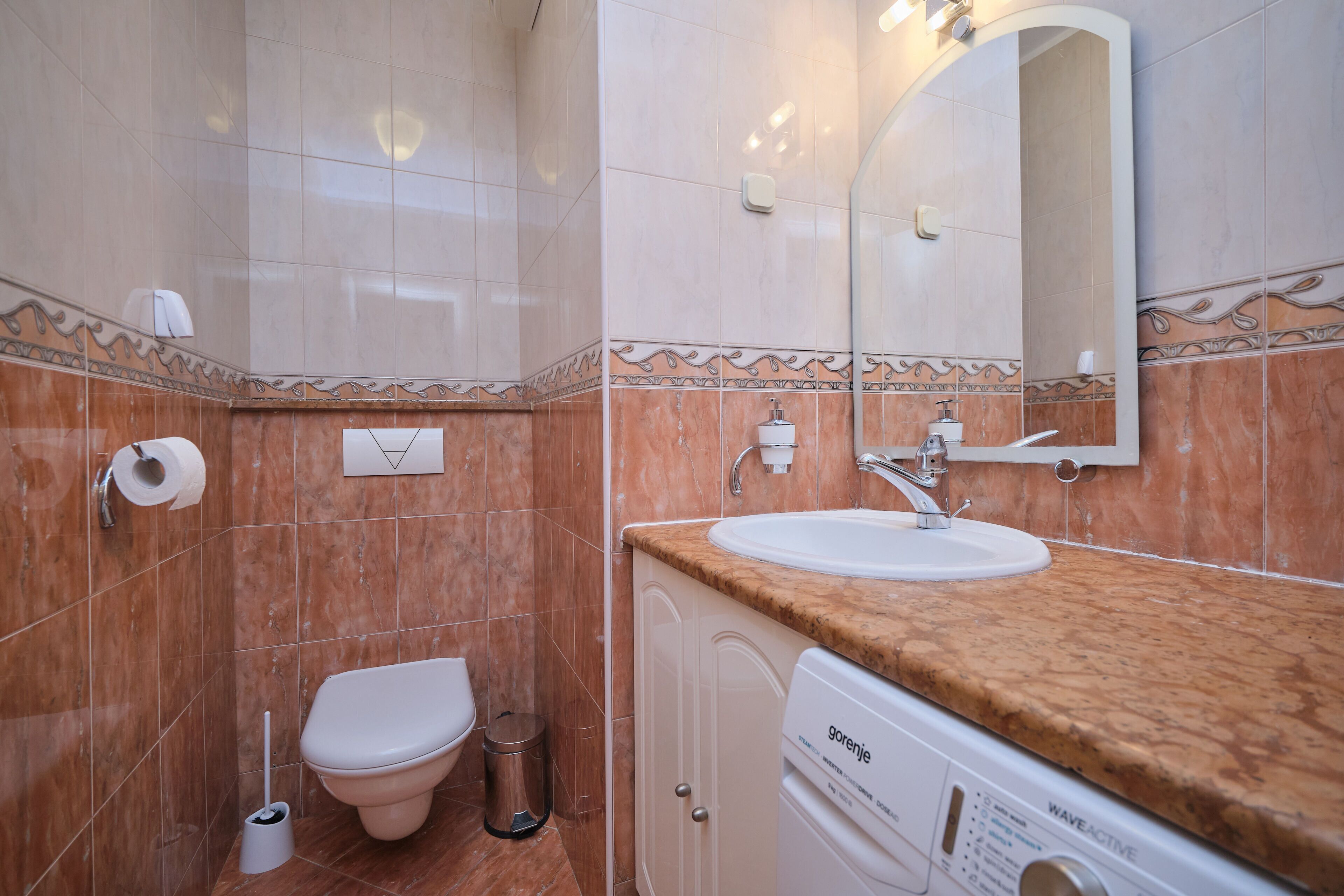 A bathroom with a toilet, sink, and washing machine.
