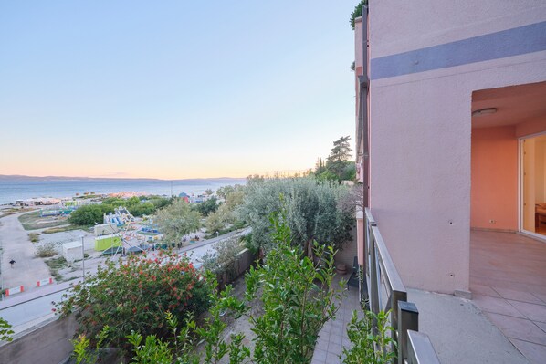 A balcony with a view of the sea and a landscaped garden.