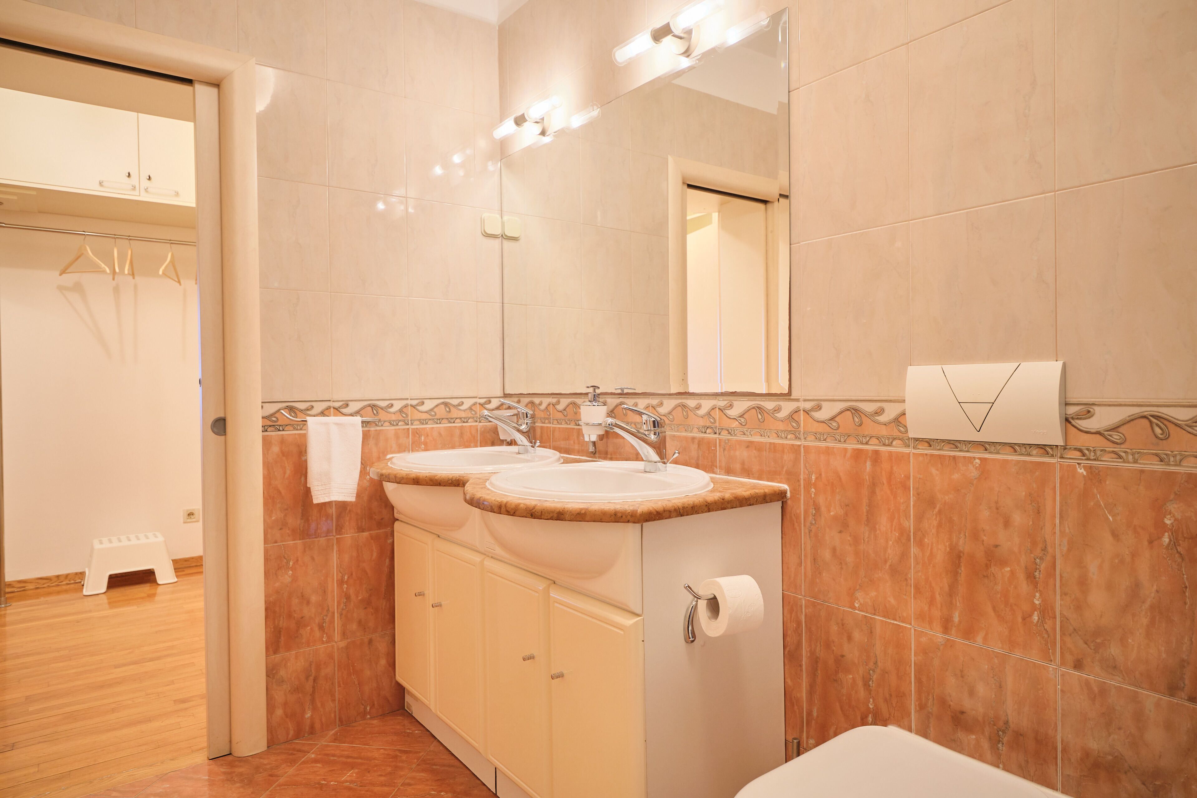 A bathroom with two sinks, a mirror, and a toilet.