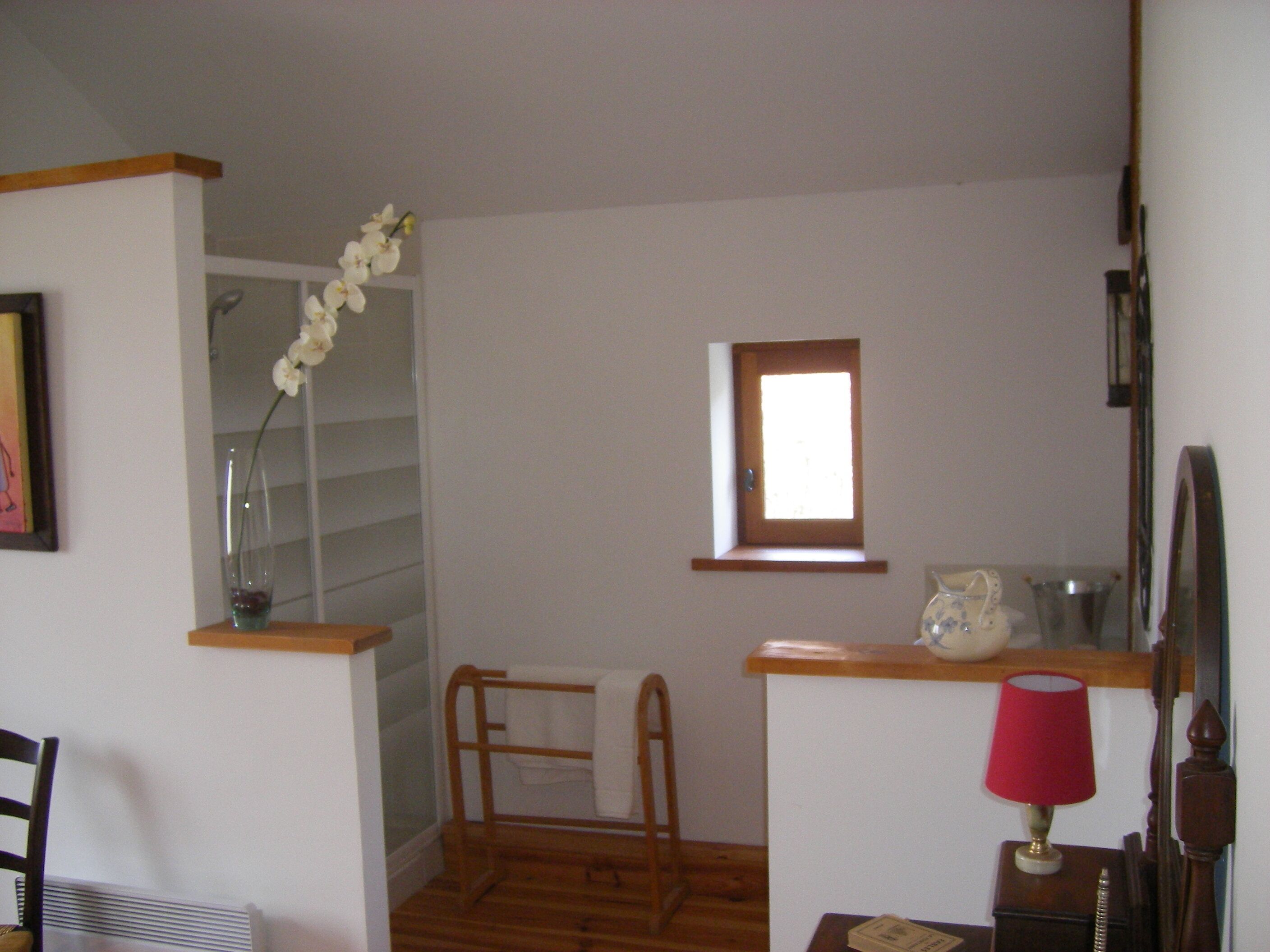 Ein kleiner, kompakter Raum mit Holzboden, einem Fenster, einer Holzablage, einer roten Lampe und einem weißen Handtuch an einem Haken.