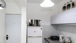 A compact kitchen with white cabinets, a white refrigerator, a kettle, and a sink. - Eilat Apartments  (Eilat)