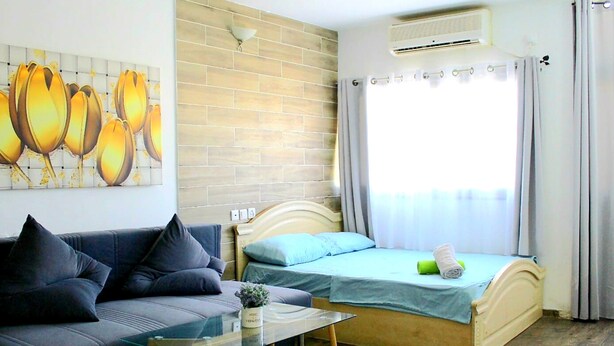 A room with a bed, a sofa, a glass table, a wall-mounted air conditioner, and a window with curtains. - Eilat Apartments  (Eilat)
