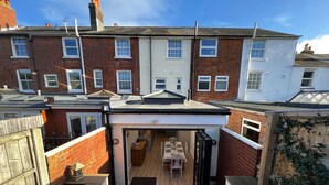 A small, enclosed patio area with a table and chairs, surrounded by a brick wall and a white fence. - York Street (Cowes)