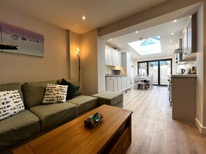 A modern living room with a sofa, coffee table, and a painting of boats.