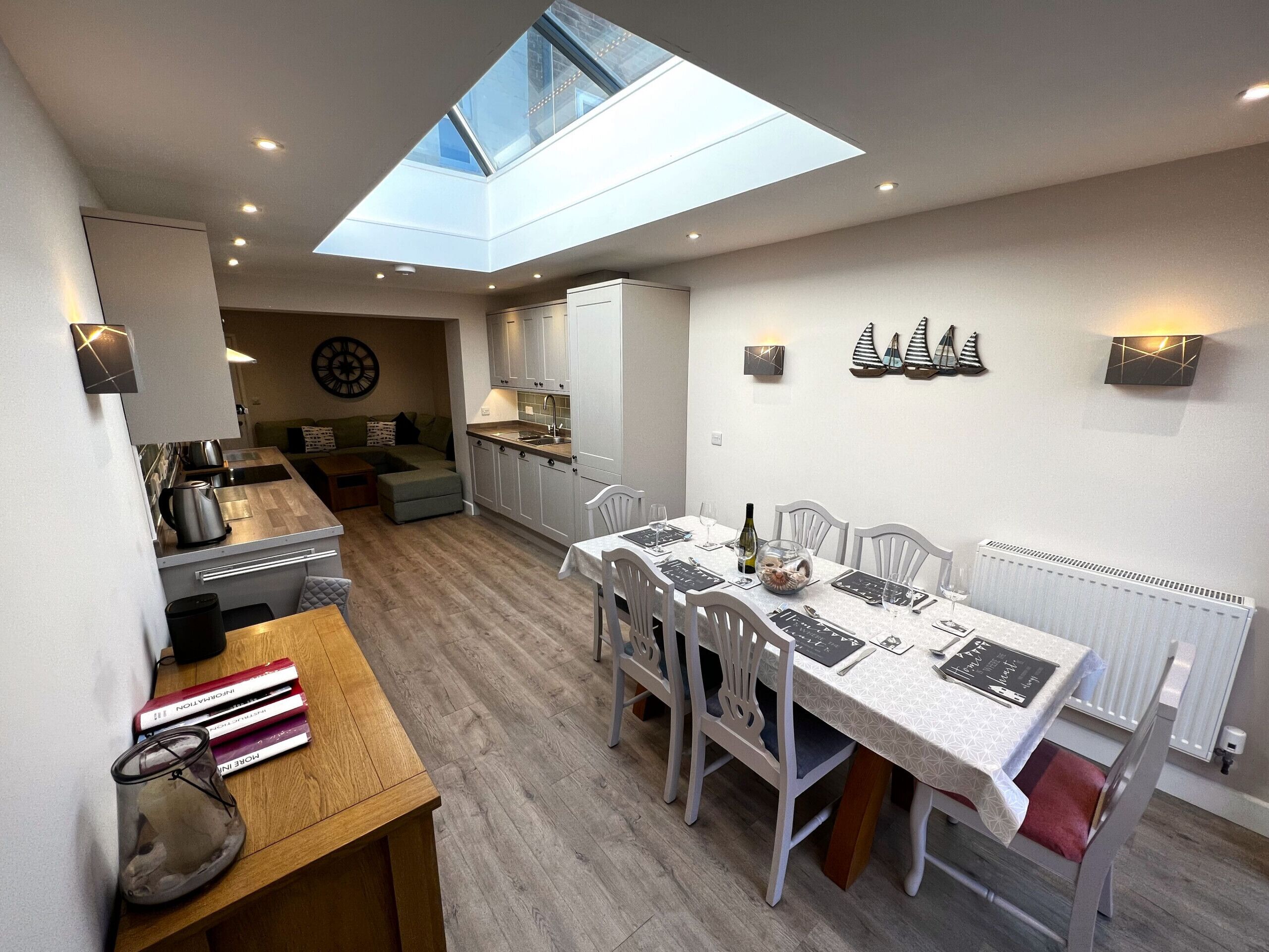 A compact kitchen with a skylight, a dining area with a table set for four, and a cozy seating area with a sofa.