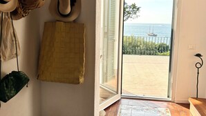 A room with a view of the sea, a tiled floor, and a door leading outside. - Bouganville  (Ischia)