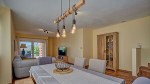 A living room with a dining table, sofa, and television. - Anovi Holiday House by Litto (Okrug)