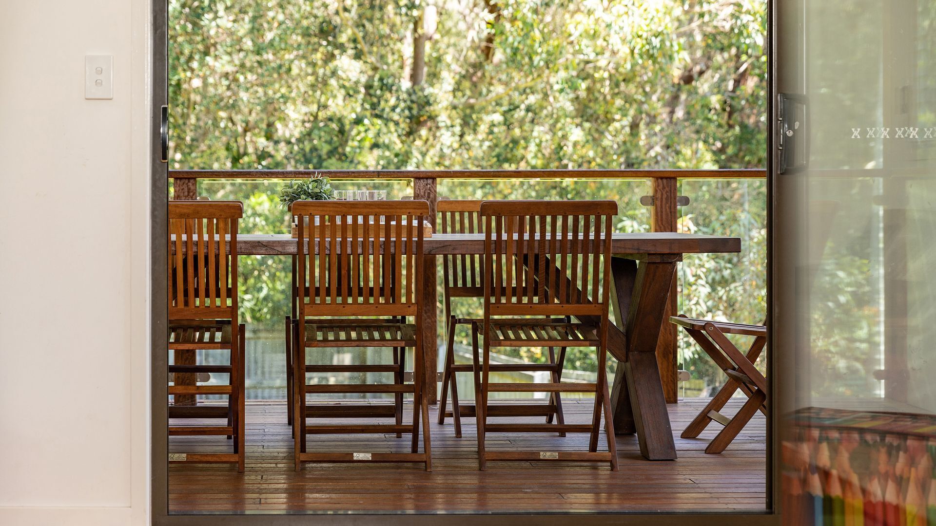 A wooden deck with a table and chairs, overlooking a forested area.