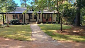 Uma casa de dois andares com varanda coberta e um jardim frontal.