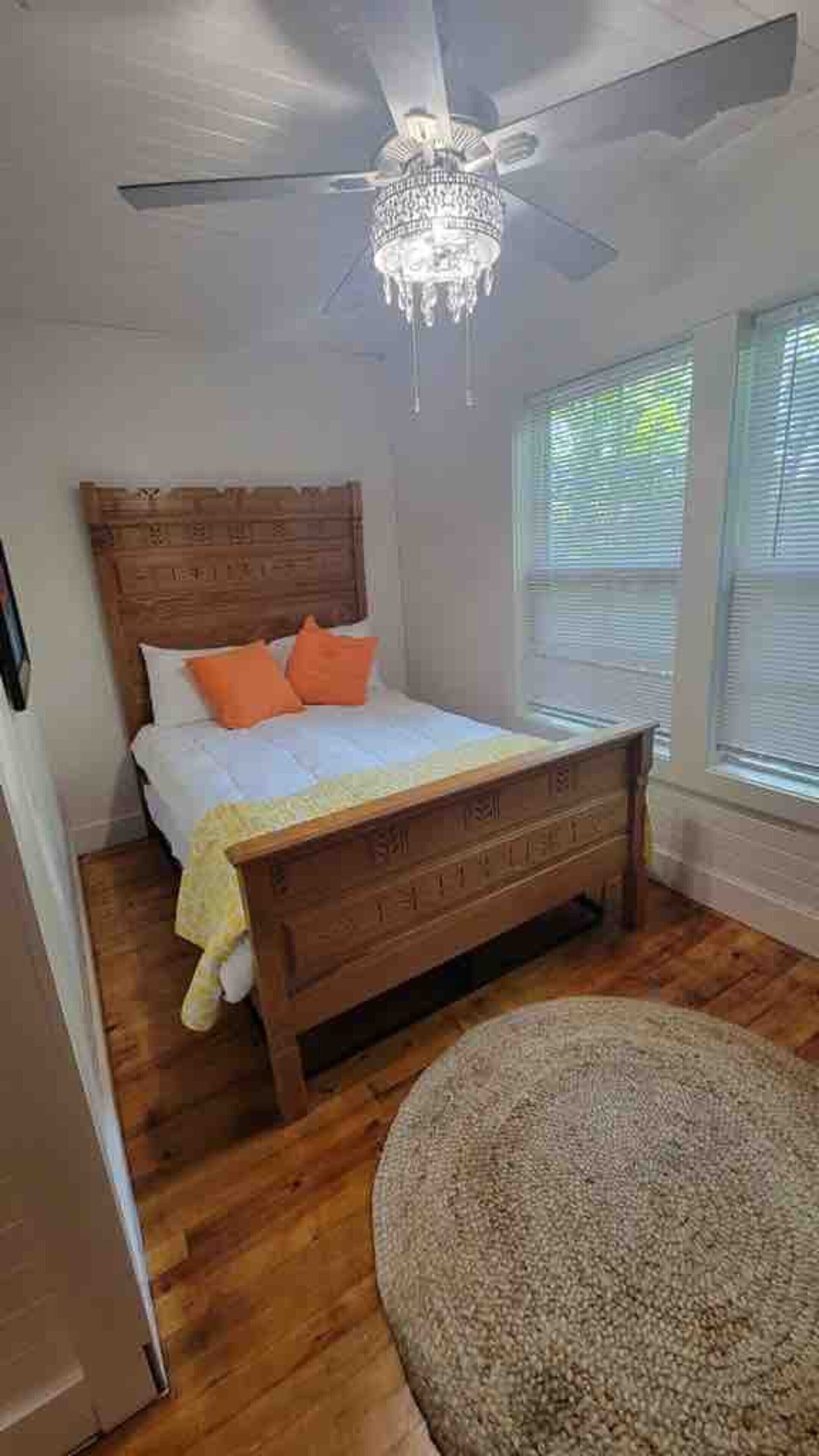A bedroom with a wooden bed, a ceiling fan, and a window with blinds.